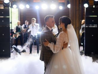 blur-faceless-musician-standing-singing-song-with-band-while-newlyweds-dancing-first-wedding-dance-centre-hall-smoke-effects_8353-12556