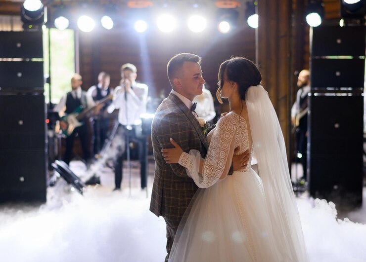 blur-faceless-musician-standing-singing-song-with-band-while-newlyweds-dancing-first-wedding-dance-centre-hall-smoke-effects_8353-12556