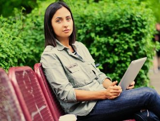 portrait-attractive-brunette-female-sits-bench-holds-tablet-pc-summer-park_613910-14416