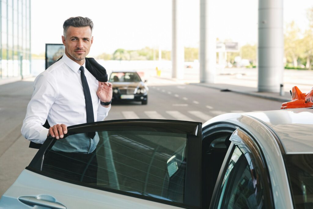 smiling-mature-businessman-getting-in-taxi-outside-1024x682