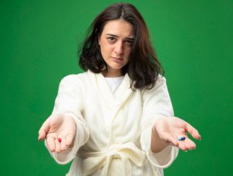 confident-young-caucasian-ill-girl-wearing-robe-stretching-out-medical-capsules-towards-camera-looking-camera-isolated-green-background_141793-78083