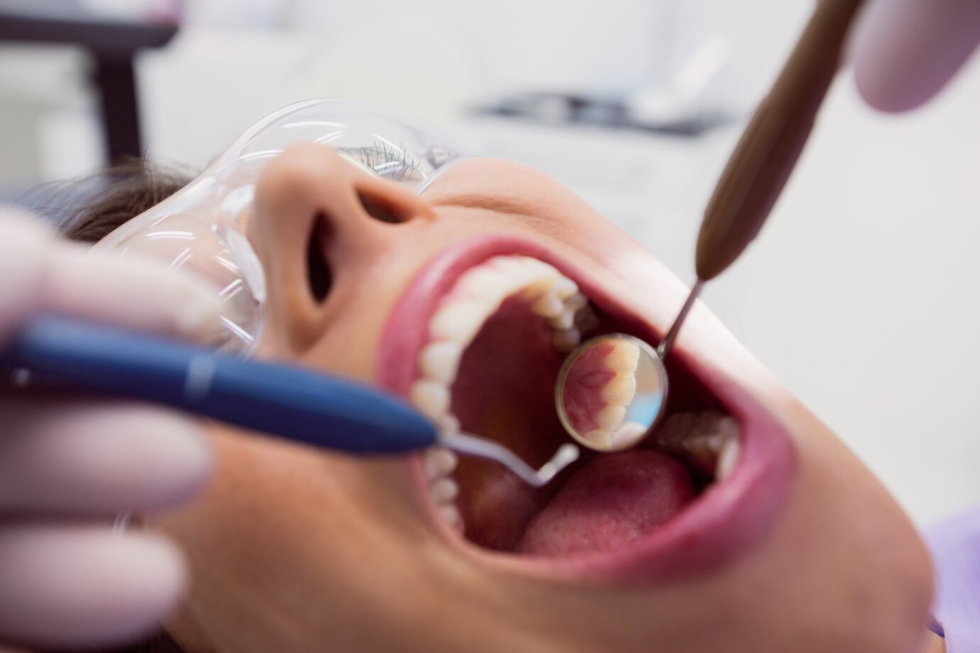 dentist-examining-female-patient-with-tools_107420-65513