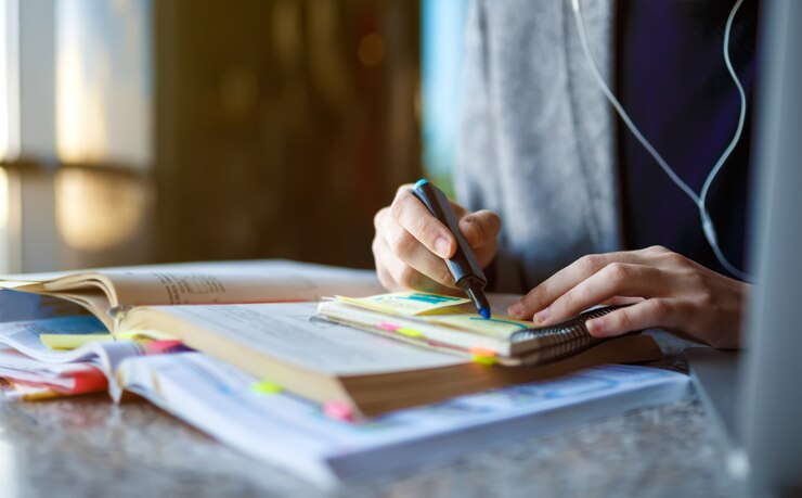 shot-young-male-student-sitting-table-writing-notebook-young-male-student-studying-cafe_217236-342